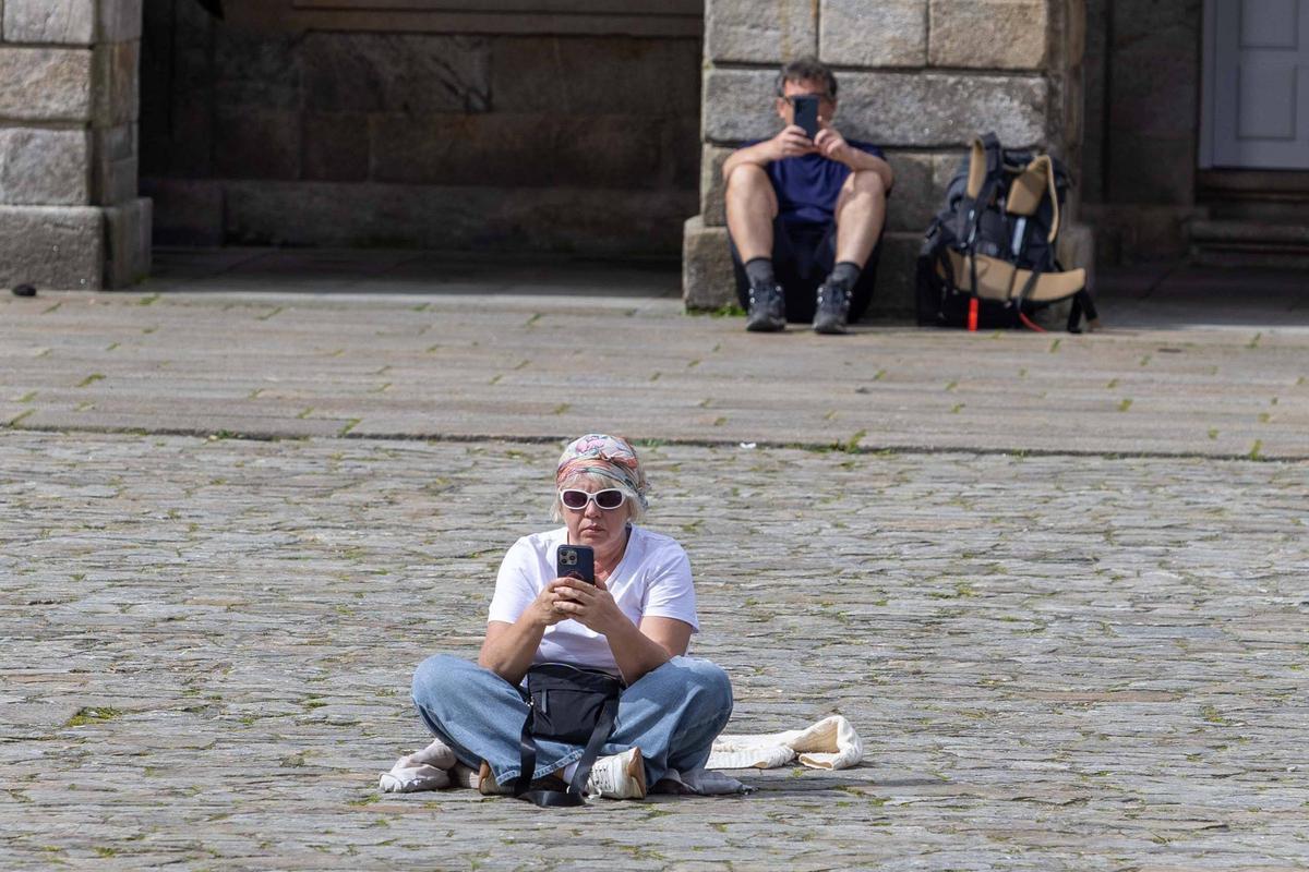 Dos turistas descansando en la Praza do Obradoiro de un Santiago que ha visto caer en picado las cifras de ocupación hotelera en este 2026.