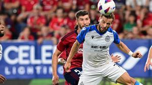 El delantero del Brujas Andreas Skov Olsen (d) cabecea un balón ante David García, de Osasuna, durante el partido de la Liga Conferencia que Osasuna y Brujas disputan este jueves en el estadio de El Sadar, en Pamplona. EFE/Iñaki Porto