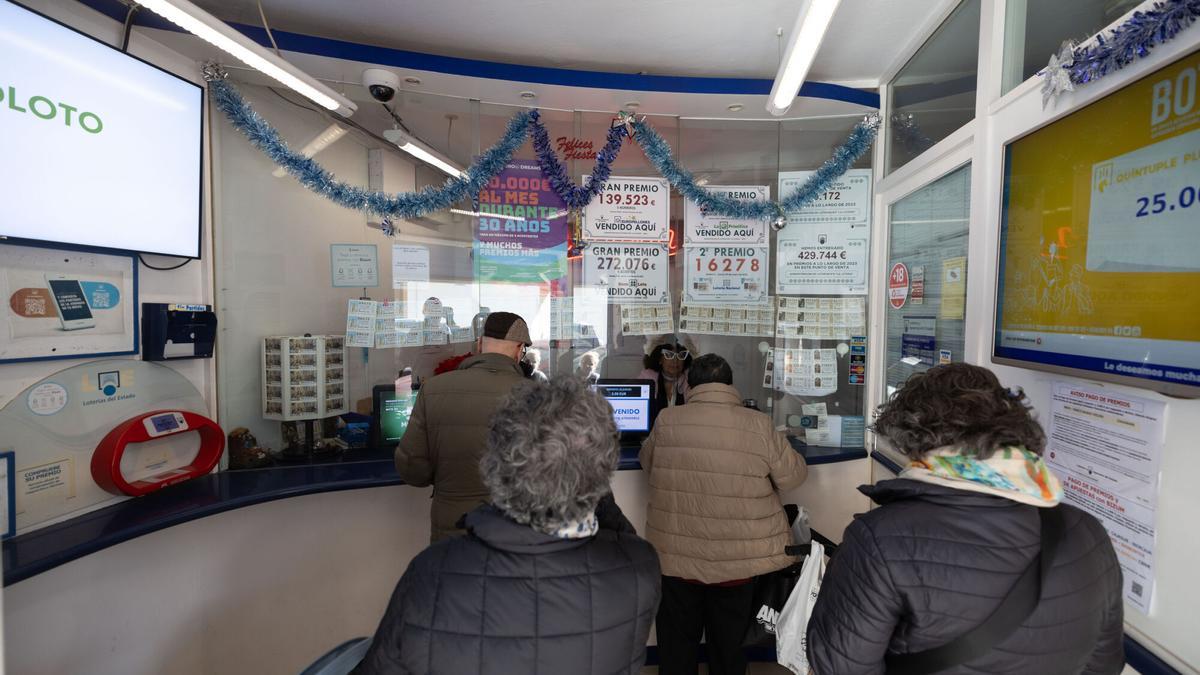 Varias personas comprando décimos de la Lotería de Navidad 2024 en una administración