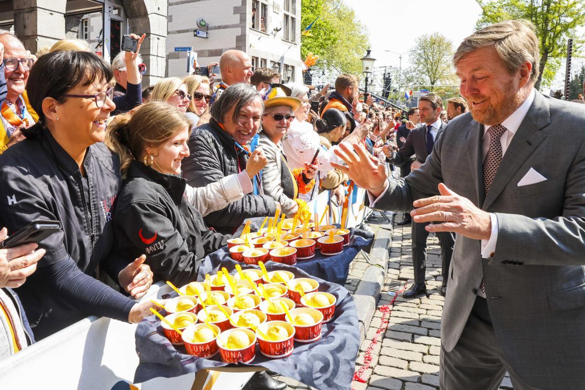 El rey de Holanda se dispone a probar un helado que le ofrecen algunos ciudadanos de Maastricht, durante la celebración del Día del Rey.
