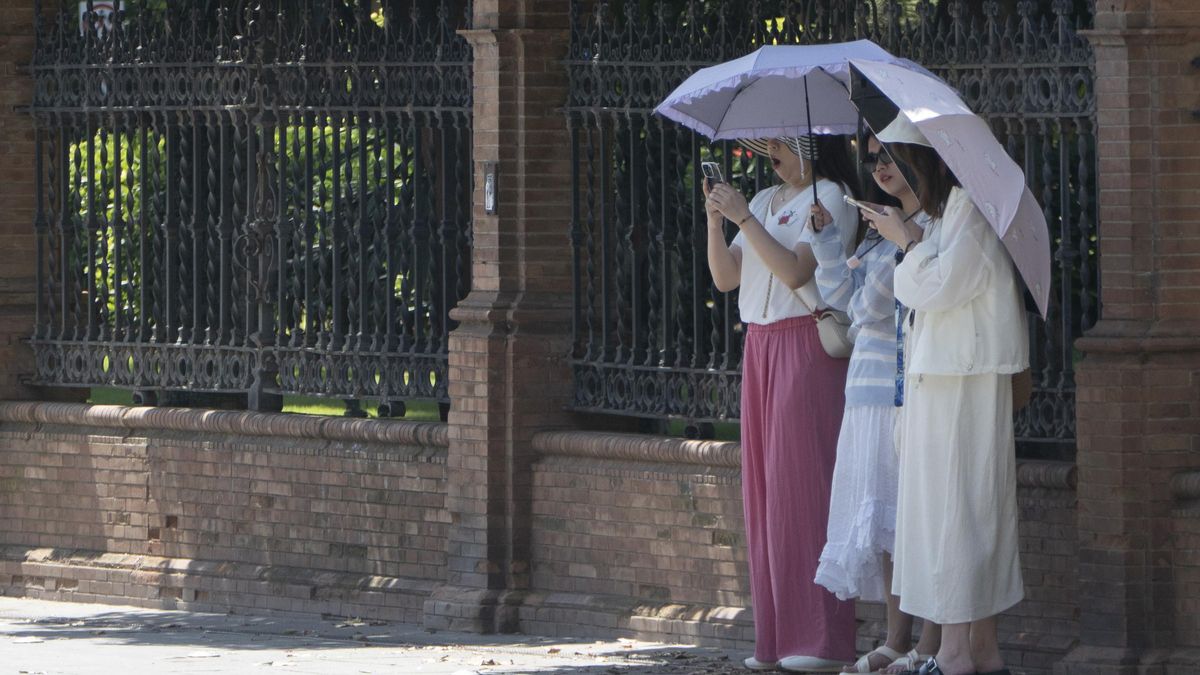 Tres mujeres protegiéndose del calor con sombrillas.