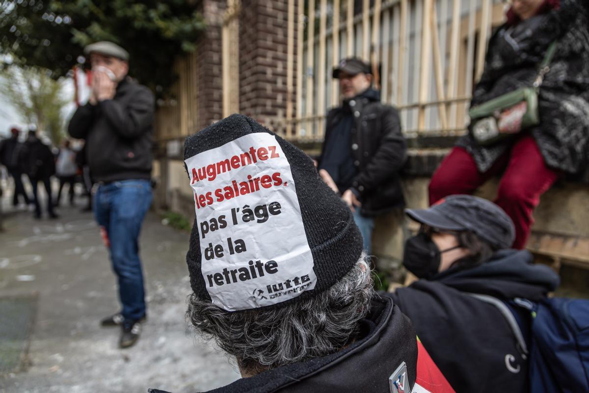 Ivry-sur-seine (France), 17/03/2023.- A French labor union member wears a hat with a sticker reading ’Increase wages not retirement age’ as striking employees block the deposit of garbage collection dump trucks to protest against the government’s pensions reform law in Ivry-sur-Seine, near Paris, 17 March 2023. Tons of waste and rubbish are piling up on the streets of Paris after a week of strike action by dustbin collectors. French Prime Minister Borne on 16 March 2023 announced the use the Article 49 paragraph 3 (49.3) of the French Constitution to have the text on the controversial pension reform law be definitively adopted without a vote in the National Assembly (lower house of parliament). The bill would raise the retirement age in France from 62 to 64 by 2030. (Protestas, Francia) EFE/EPA/CHRISTOPHE PETIT TESSON