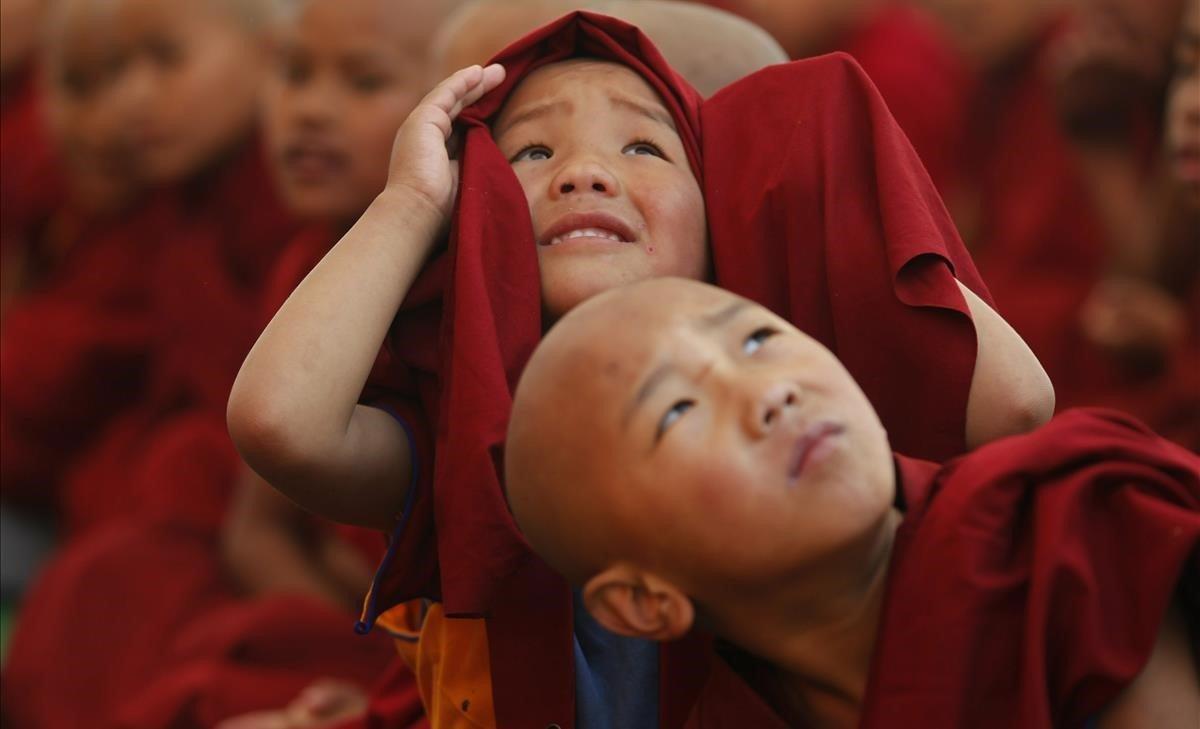 Jóvenes monjes se distraen con un dron durante una danza tradicional en el festival de danza Cham, parte de las celebraciones del Año Nuevo Tibetano en el Monasterio Triten Norbutse en Katmandú, Nepal.