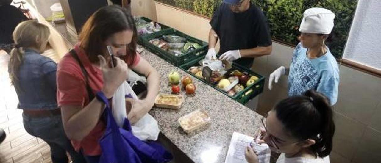 Varios voluntarios reparten alimentos en el comedor social El Puchero, en el barrio de Orriols en València.