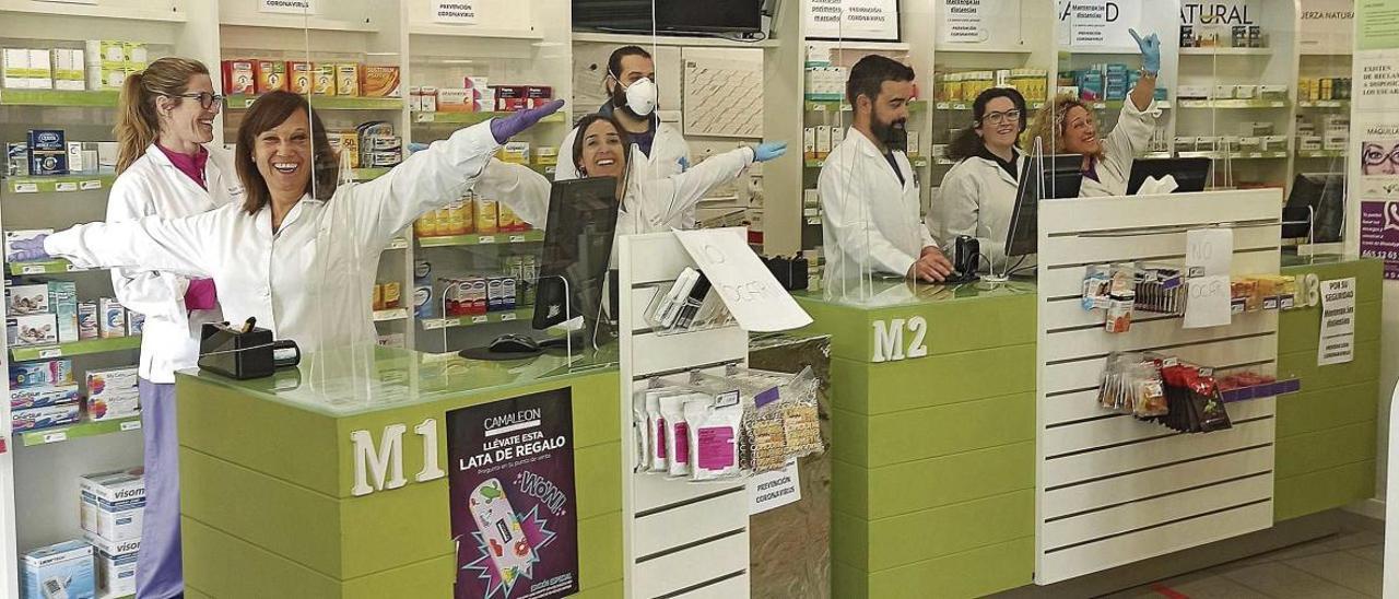 El personal de una farmacia celebra la instalaciÃ³n de sus mamparas protectoras.