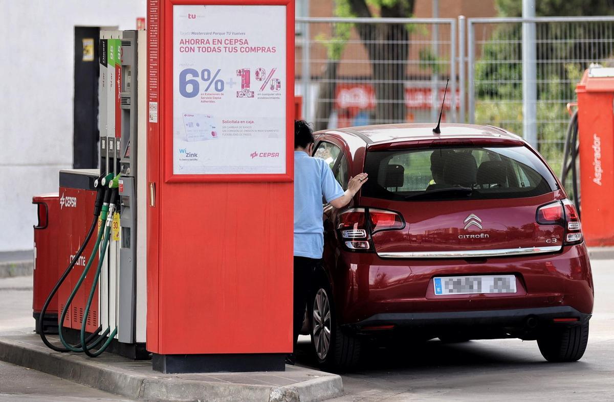 Una mujer repostando en una gasolinera.