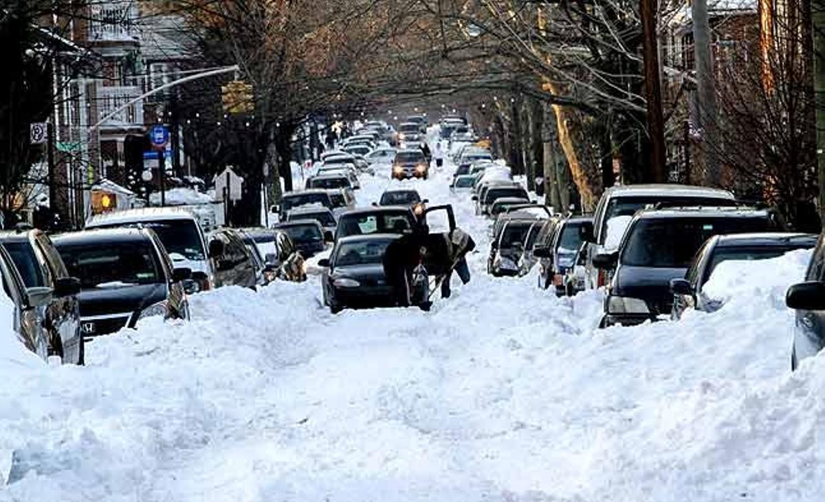 Dues persones caven a la neu per alliberar un cotxe encallat al carrer 56 a la zona de Boro Park del comtat de Brooklyn, a Nova York (Estats Units).