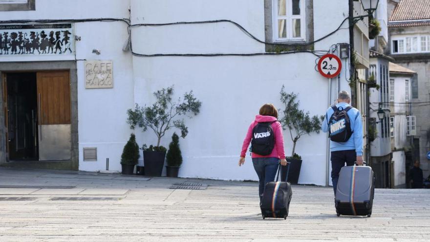 Dos turistas con sus maletasm en Snatiago. | Antonio Hernández