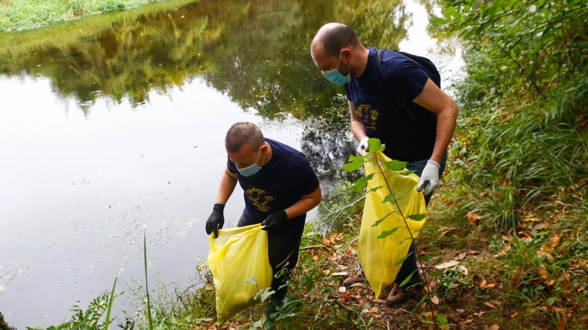 Dos hombres recogen residuos en la orilla del río Umia