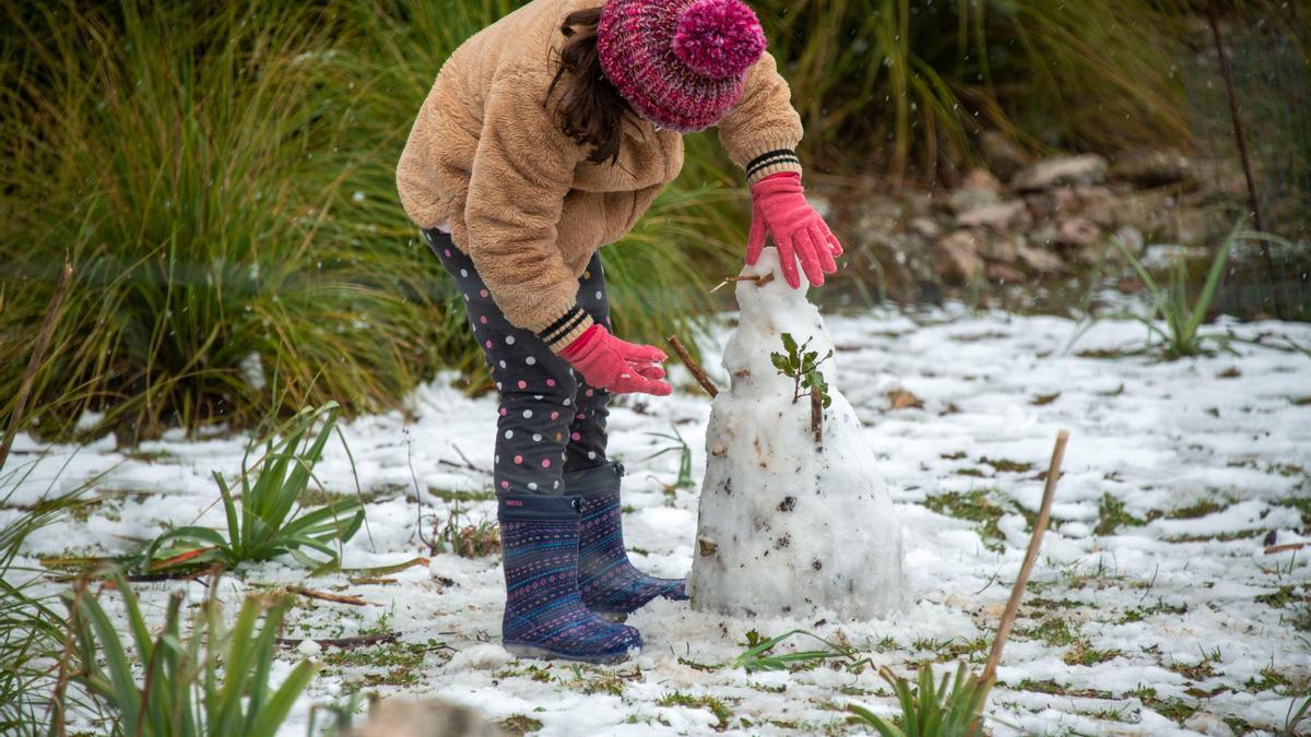 Una niña hace un muñeco de nieve en la zona del embalse de Cuber