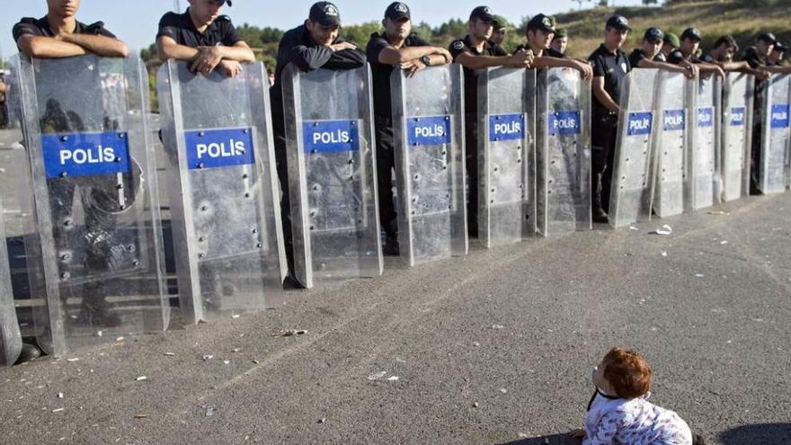 Un bebé sirio juega delante de una barrera de antidisturbios turcos en Edirne.