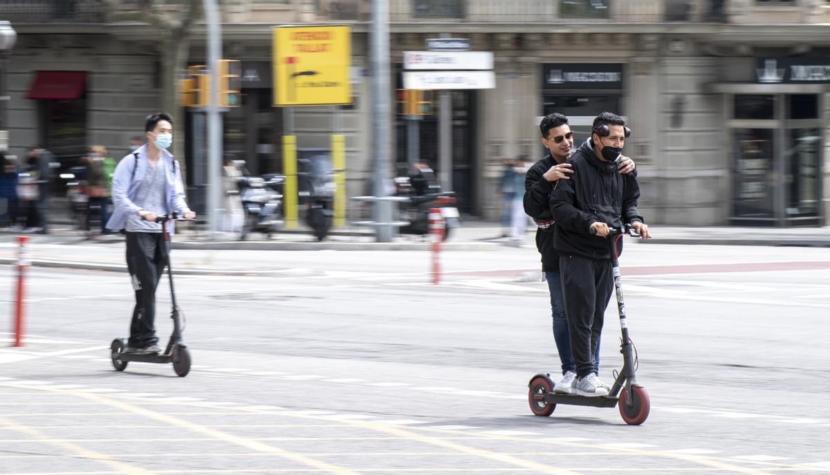 Patinetes por la avenida Diagonal. Uno de ellos, con dos ocupantes; mal...