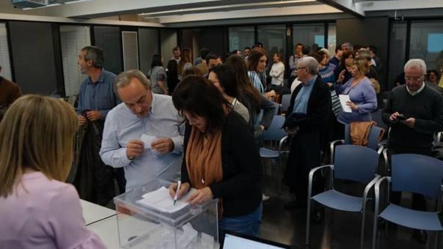 Asistentes a la asamblea depositan su voto en la urna.