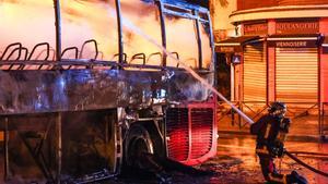 Cuarta noche de disturbios en Francia. Los bomberos extinguen el fuego en un autobús incendiado en Nanterre.  