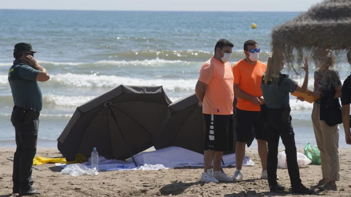 El cadáver de la mujer, cubierto con una sábana y custodiado por la Guardia Civil en la orilla de la playa.