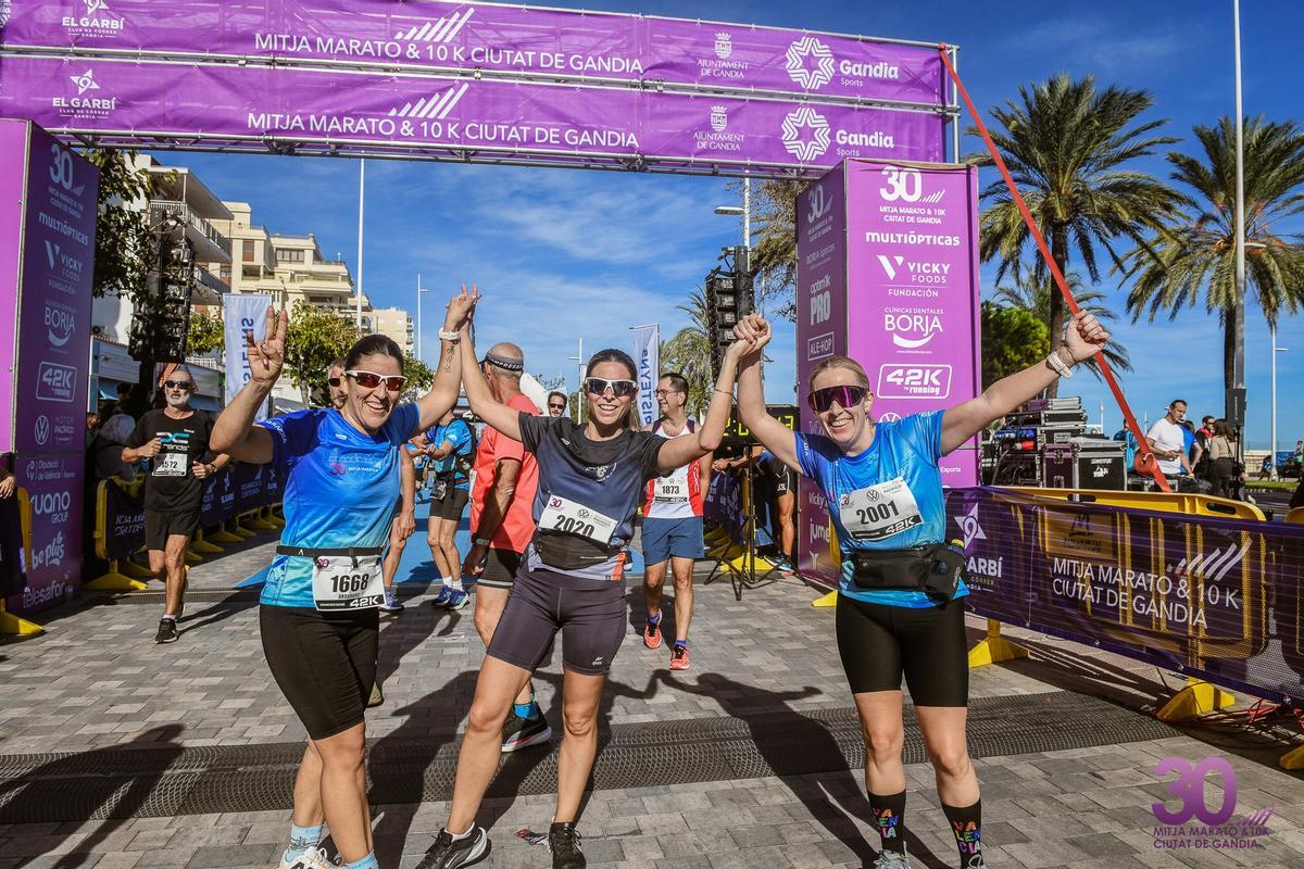 Tres chicas celebran su llegada a meta en la Mitja & 10K Gandia del año pasado