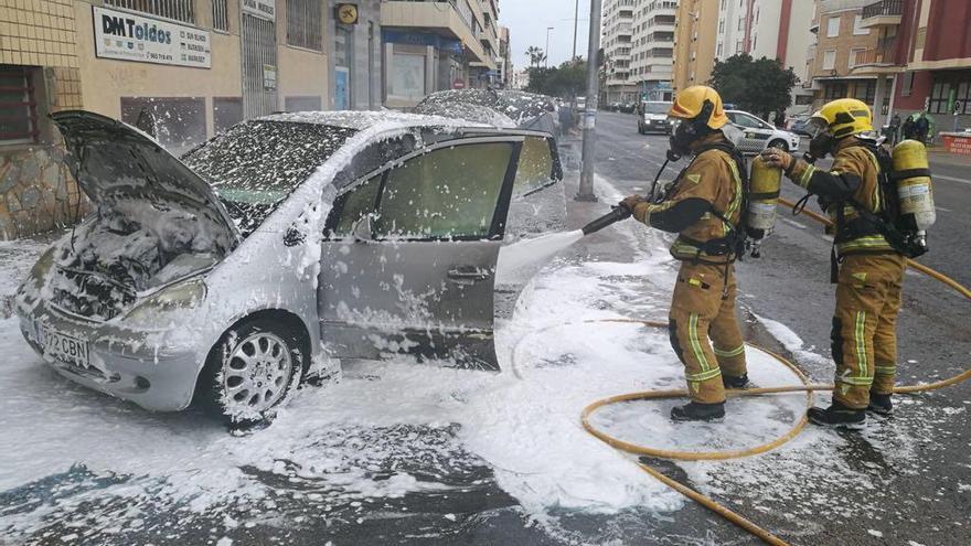 Bomberos rocían con espuma el vehículo y la calzada.