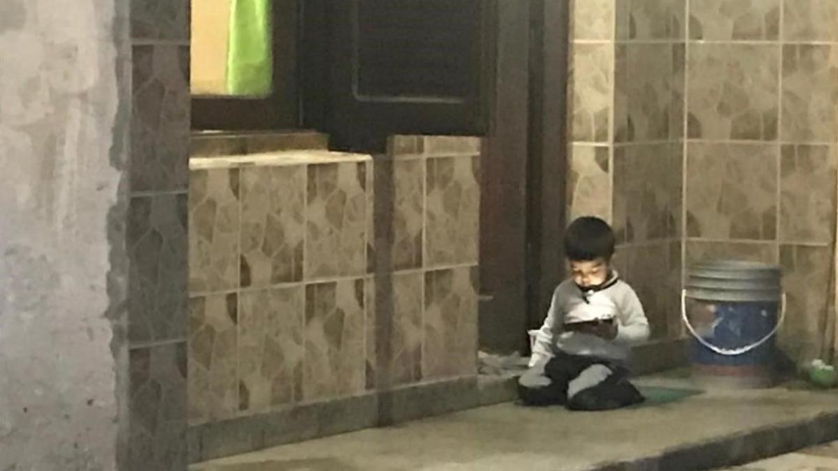 Un niño se entretiene con él móvil de su madre a las puertas de su casa de Termas de Río Hondo.