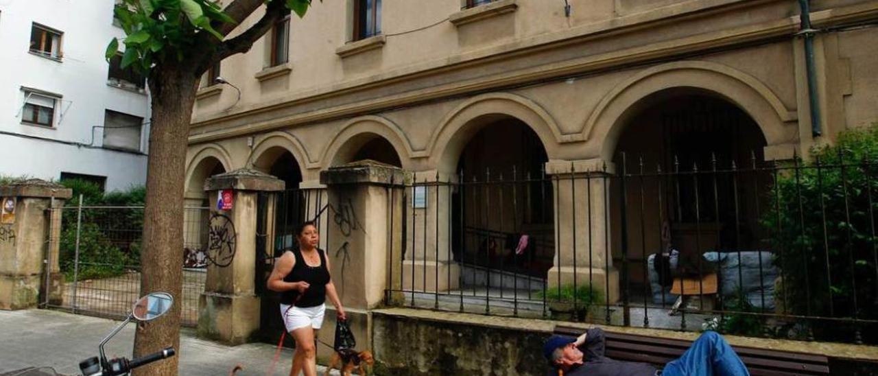 Una vecina de San Lázaro pasa ante el edificio de la Malatería, ayer a media tarde, con el porche ocupado por vagabundos.