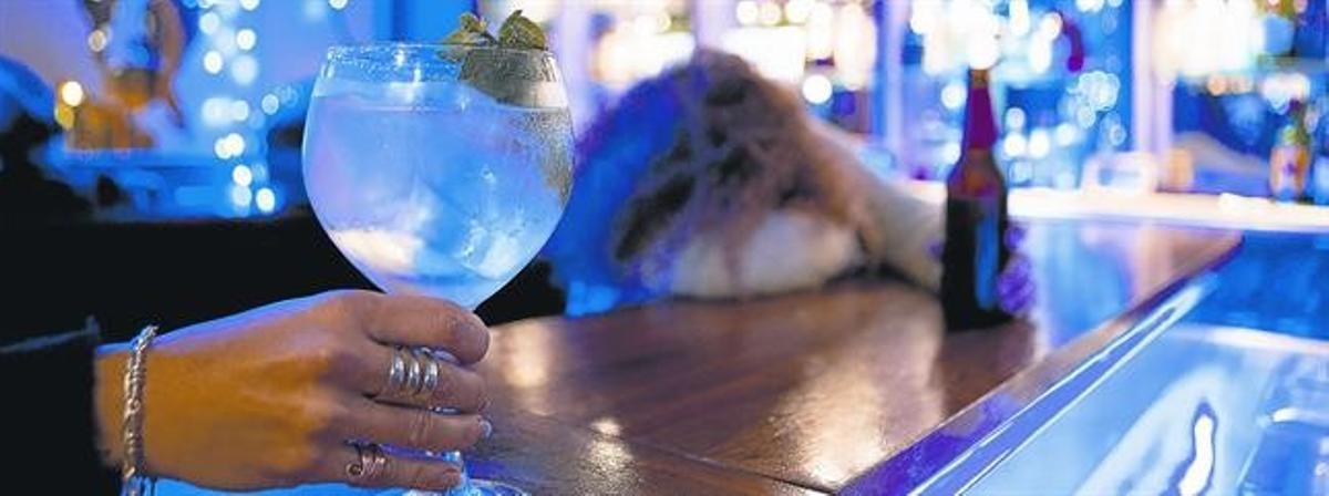 Una mujer consume una bebida en la barra de un bar.