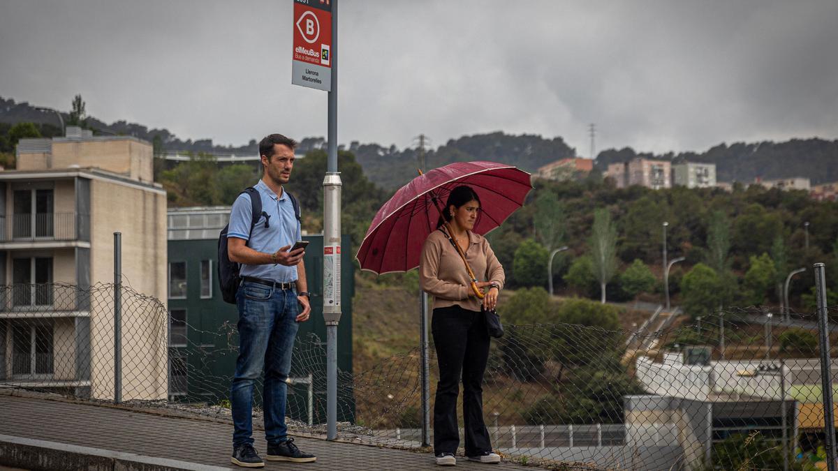 Dos vecinos en una de las paradas del bus a demanda de Torre Baró, en Barcelona.