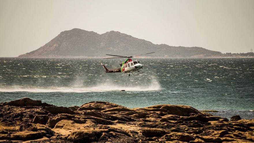 Un helicóptero coge agua para atacar el incendio de Porto do Son // Óscar Corral (Efe)