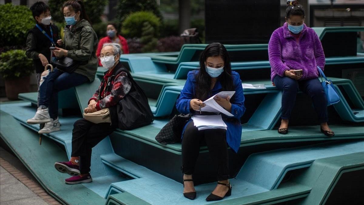 Un grupo de mujeres usan mascarillas y mantienen la distancia preventiva para evitar el contagio del coronavirus, en Hong Kong.