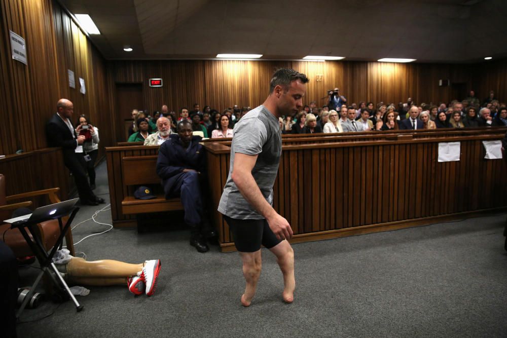 El atleta paralímpico Oscar Pistorius camina a través de la sala sin sus prótesis de piernas durante el tercer día de juicio por el asesinato de su novia Reeva Steenkamp