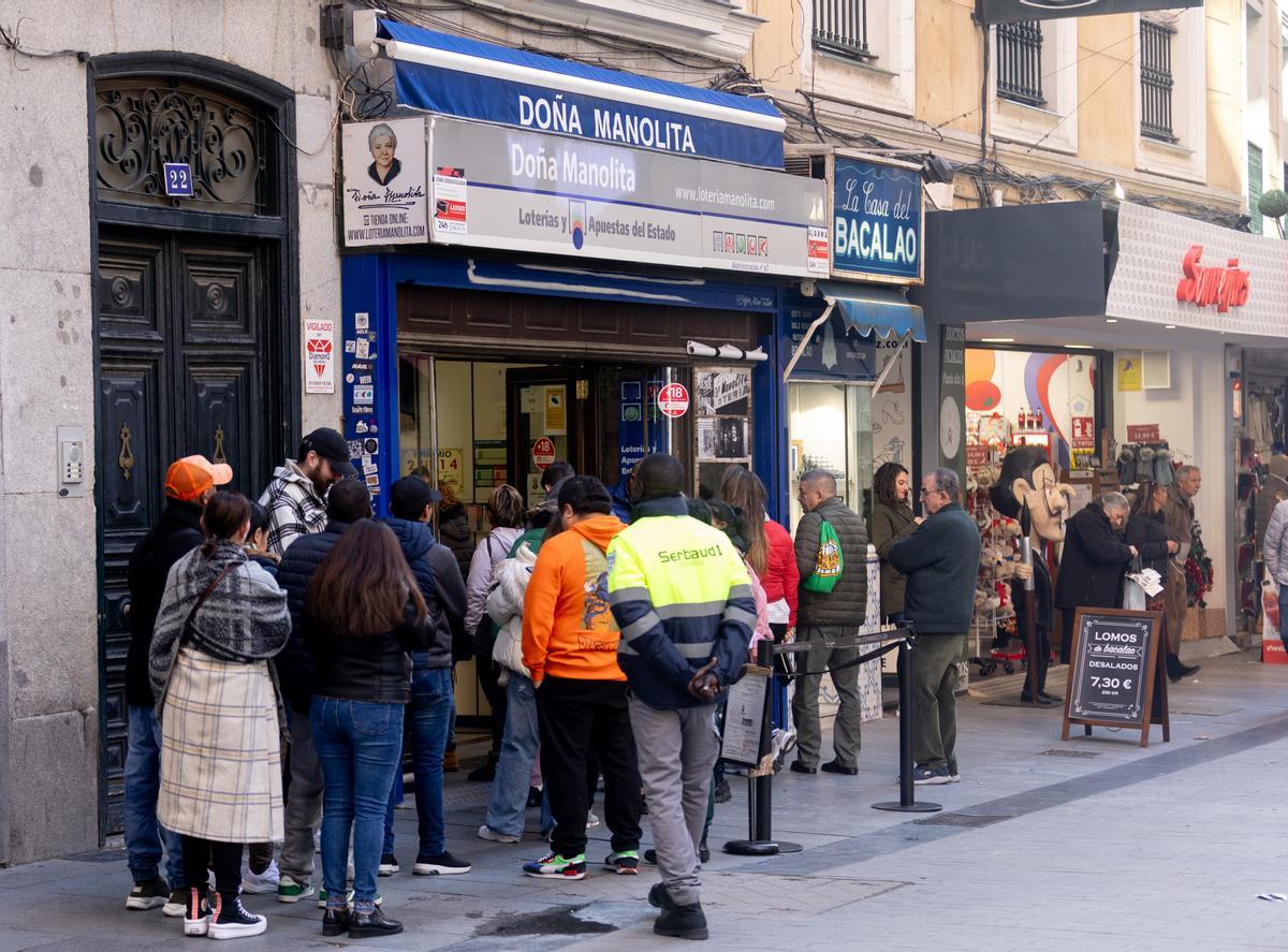 Varias personas hacen cola para comprar décimos de cara al Sorteo Extraordinario de la Lotería de Navidad, en la Administración de Loterías Doña Manolita, a 14 de diciembre de 2023, en Madrid (España).