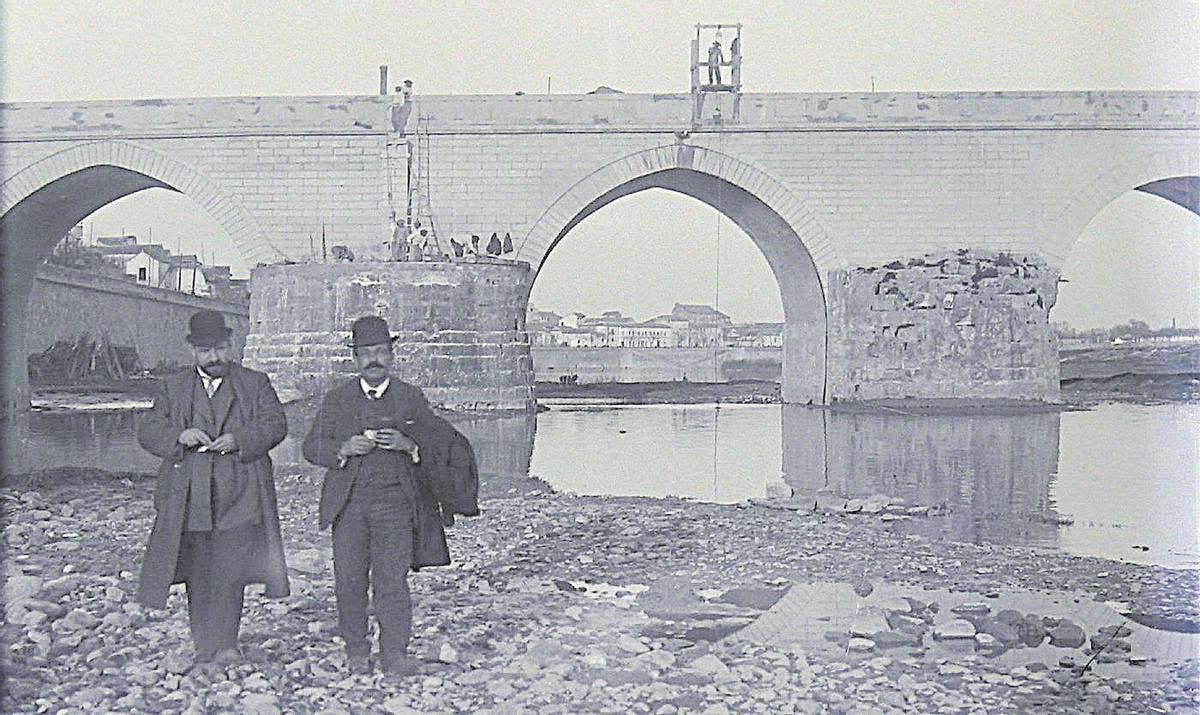 Principios del siglo XX: Dos cordobeses posan durante la restauración del Puente Romano en 1908.