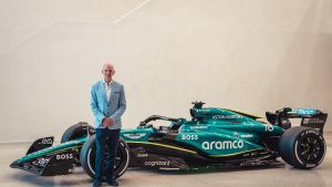 Adrian Newey posa junto a un coche de Fórmula 1 de Aston Martin.
