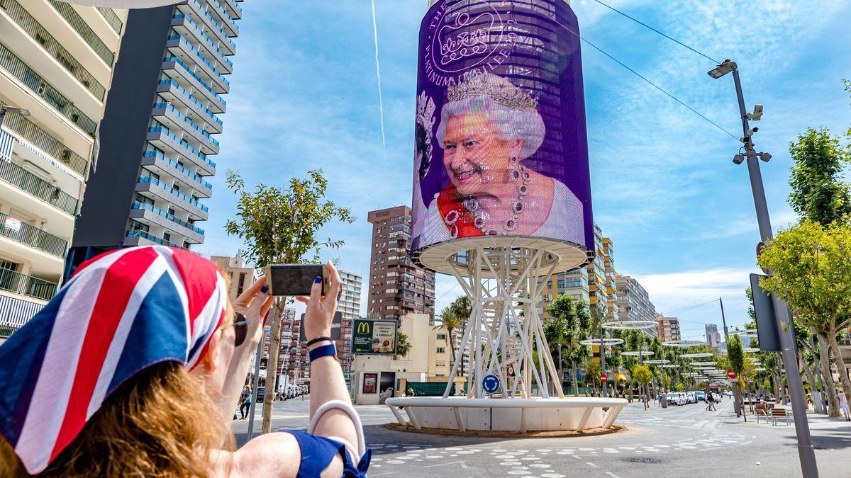 Una turista fotografía la imagen de la reina de Inglaterra reproducida en el Tecnohito de la avenida del Mediterráneo de Benidorm .