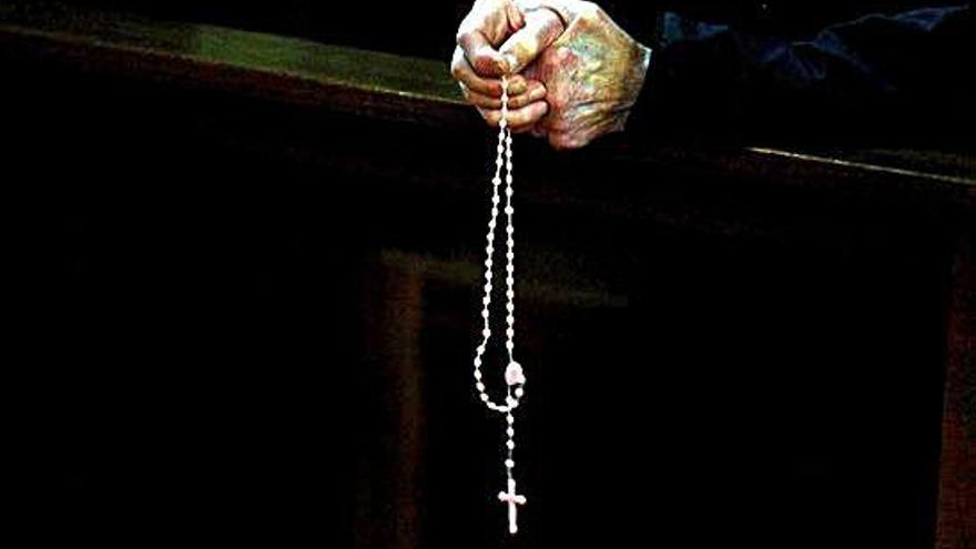 Una persona sostiene un rosario durante una eucaristía.
