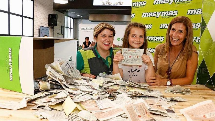 Arriba, Elisa Marrugán, acompañada por Lucy Rey -izquierda- y Luisa López, junto a numerosas papeletas de participación. Abajo, a la izquierda, diferentes momentos de la pequeña durante el sorteo celebrado ayer en las instalaciones de masymas en Intu Asturias.