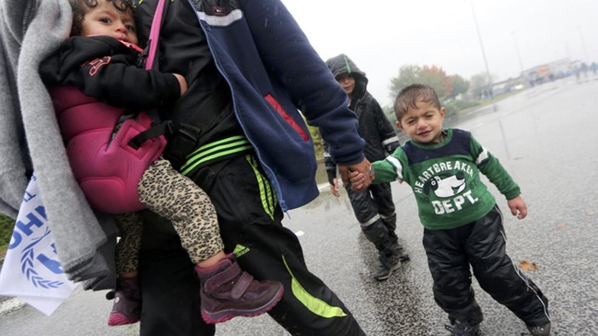 A child reacts as migrants wait in the rain in no man's land to cross the border to Slovenia from Trnovec