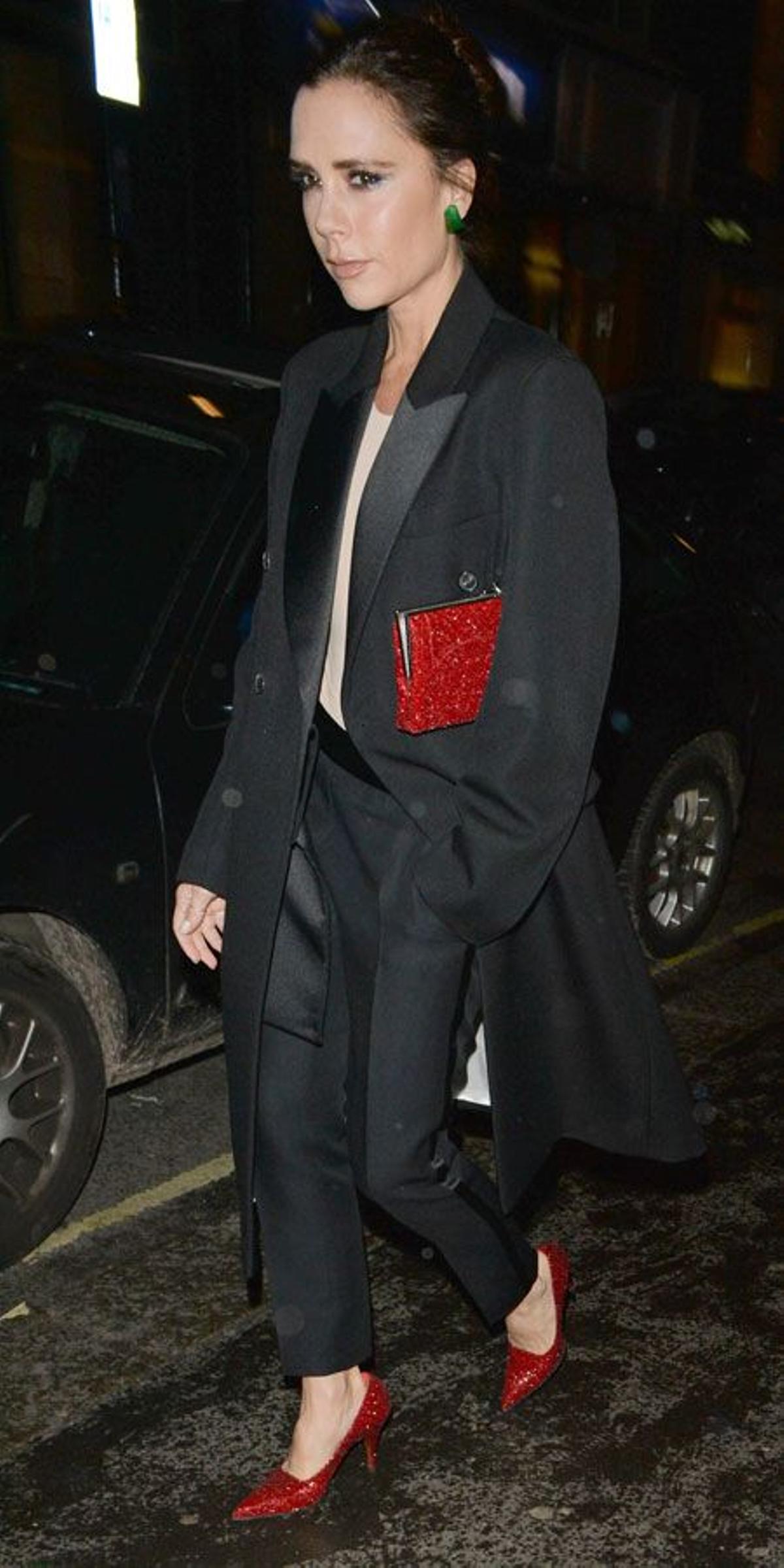 Victoria Beckham y su look masculino con accesorios rojos y pendientes en verde