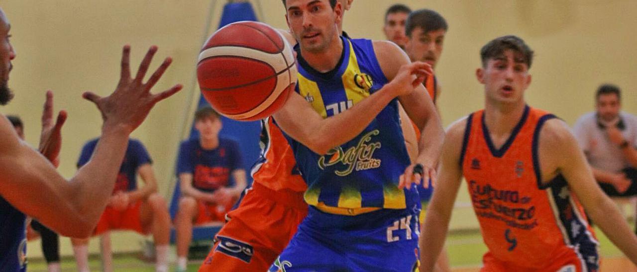 Adrián Gálvez pasa a un compañero para intentar burlar la defensa del Valencia Basket. | ALFONSO SALDAÑA