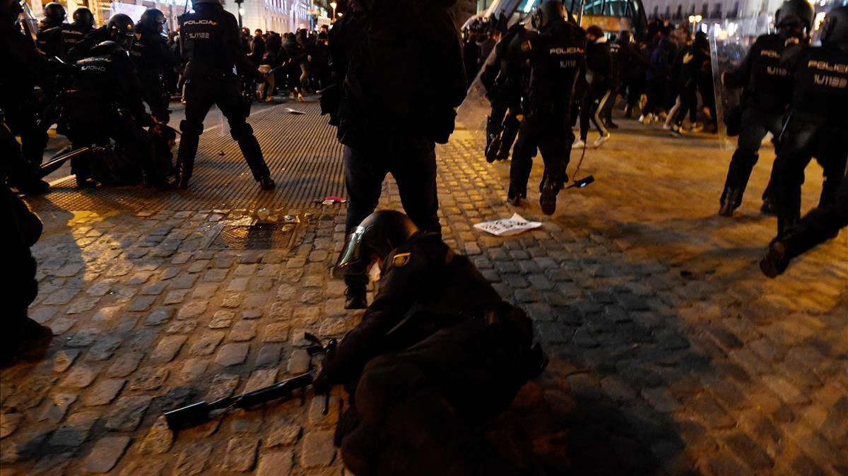 Un miembro de la Policía Nacional cae durante enfrentamientos con manifestantes, en Madrid, tras una manifestación contra el encarcelamiento del rapero.
