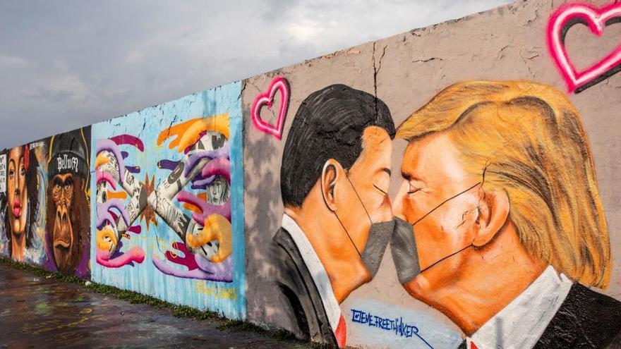 Un mural de Donald Trump y Xi Jinping besándose usando mascarillas.