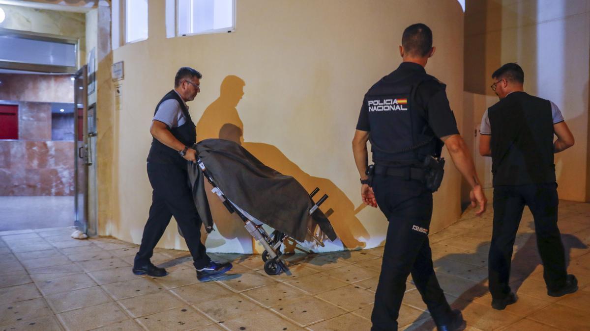 Traslado de uno de los cuerpos en la entrada del edificio donde han sido encontrados los cadáveres de un hombre y una mujer en Torrequebrada, Benalmádena.