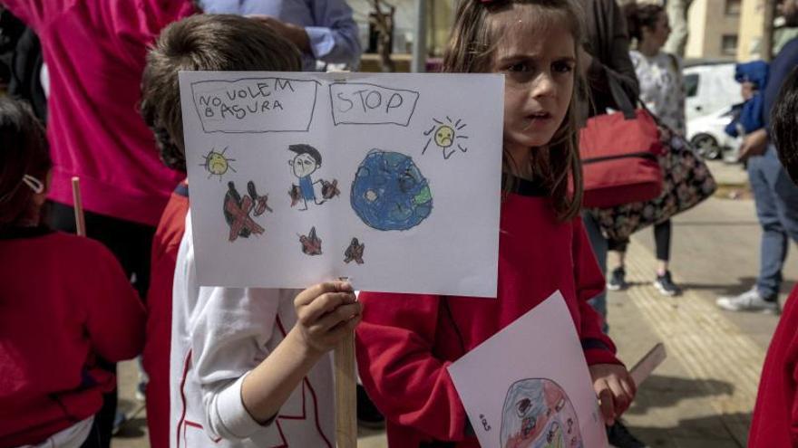 Un niño sostiene una pancarta en la que se puede leer «No queremos basura».