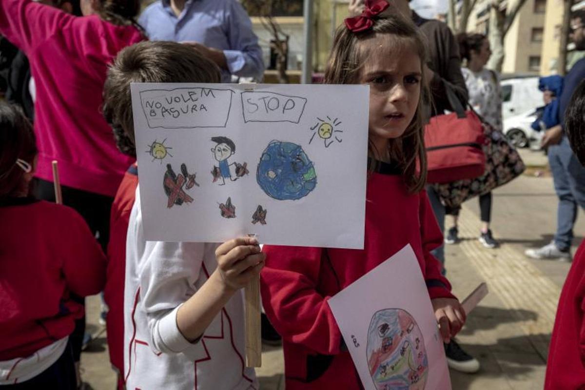 Un niño sostiene una pancarta en la que se puede leer «No queremos basura».