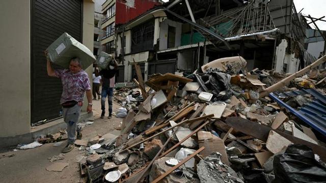 Dos homes carreguen caixes entre la runa de la ciutat de Pereira.  | LUIS ACOSTA / AFP