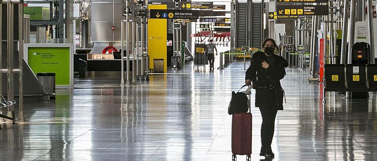 Una pasajera camina con su maleta por la planta de salidas del aeropuerto.