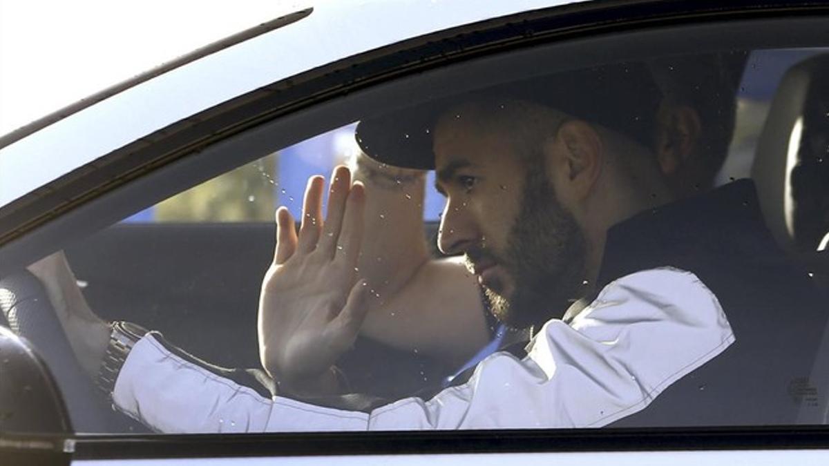 El delantero francés del Real Madrid Karim Benzema saluda a los aficionados que aguardan en la salida de Valdebebas.