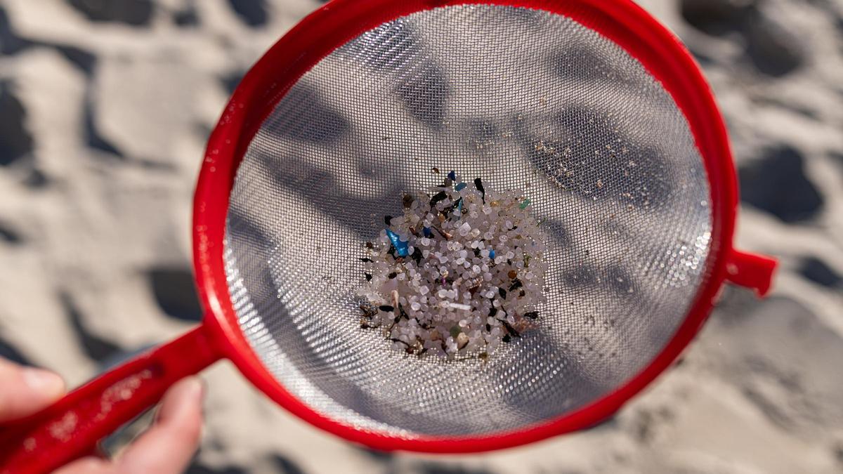 Una voluntaria recoge pellets en la arena de una playa de A Coruña