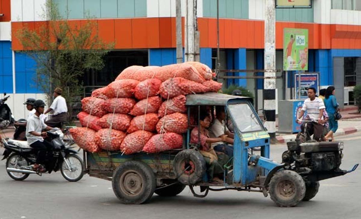 Un venedor transporta sacs de cebes cap a un basar de Mandalay, a Myanmar.