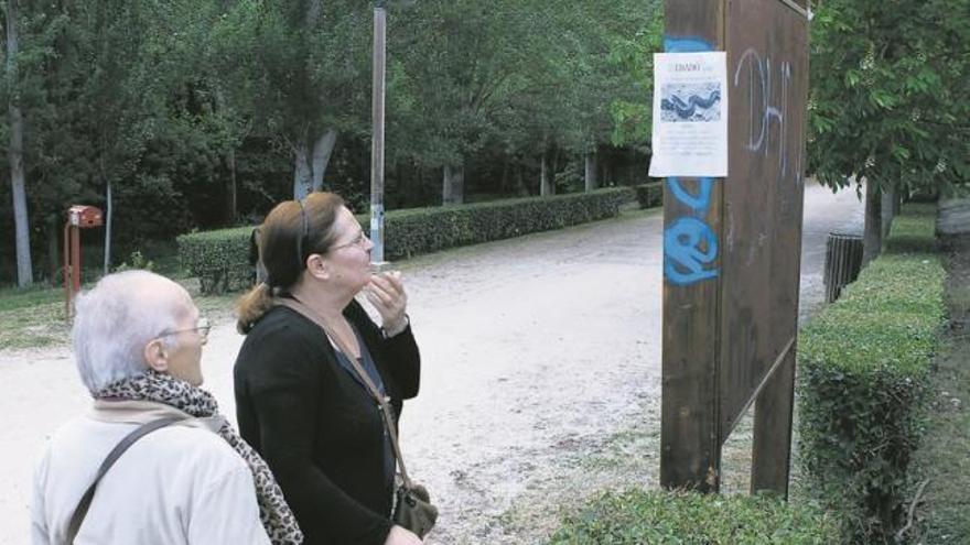 Dos mujeres observan uno de los carteles en los que se alerta sobre la plaga.