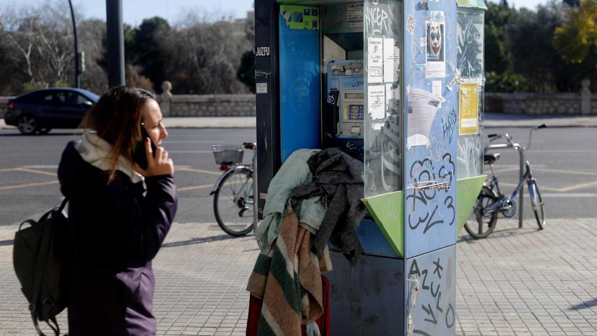 Poderoso contraste: una cabina  descuidada y una joven hablando por teléfono.  | J.M.LÓPEZ