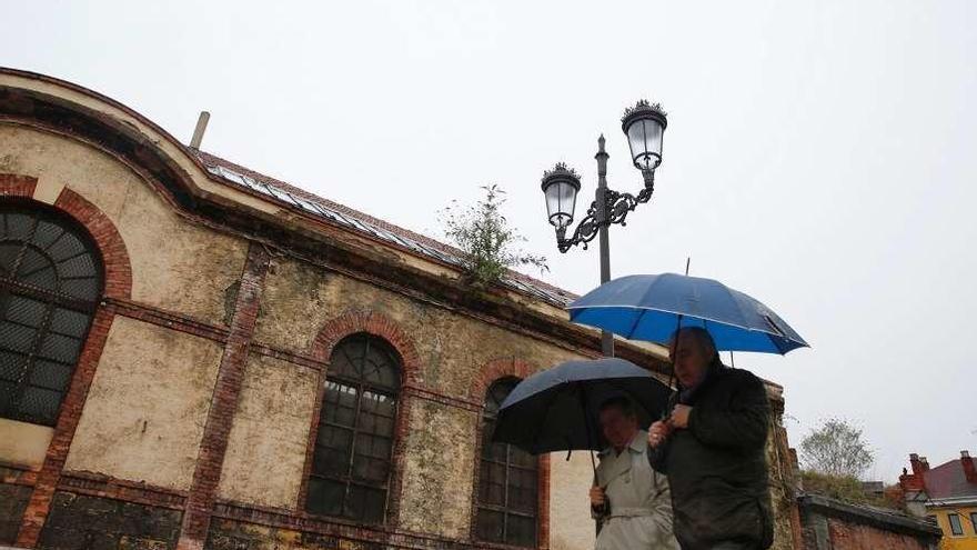 Dos personas pasan por delante de la Fábrica de Gas.